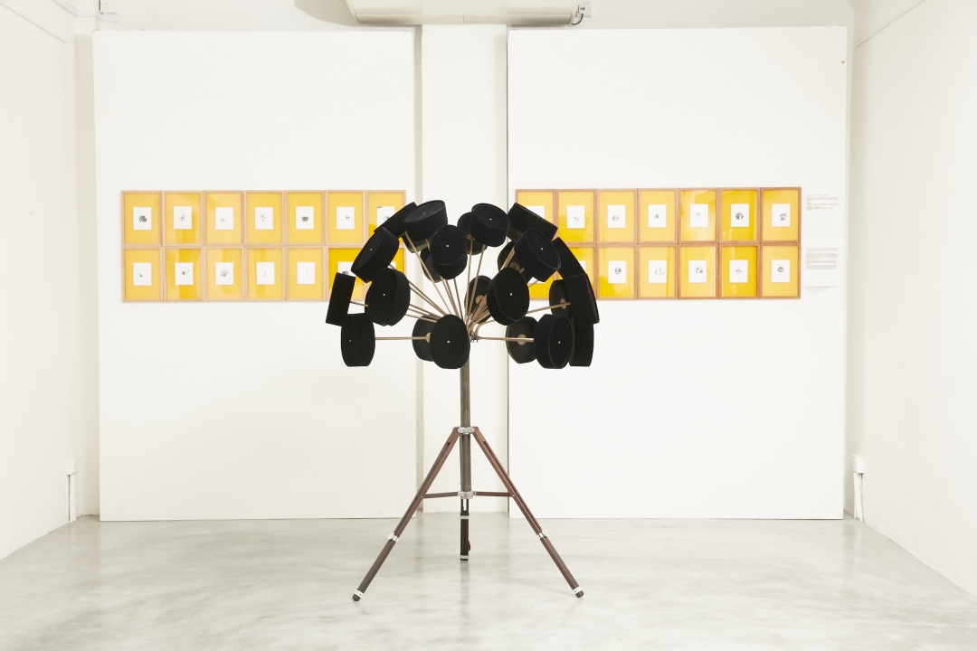 Boedi Widjaja, <i>Imaginary Homeland: 放下武器跟我走 (LAY DOWN YOUR WEAPON, FOLLOW ME)</i>, 2016, 28 pecis (traditional Indonesian hats), brass, chrome, foam, vintage camera tripod; and 28 peci pinhole negatives on Ilford paper in individual frames, 55 x 66 in. (140 x 168 cm)